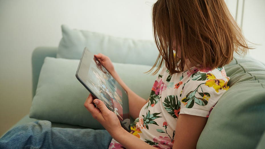 Little girl on iPad while sitting on couch
